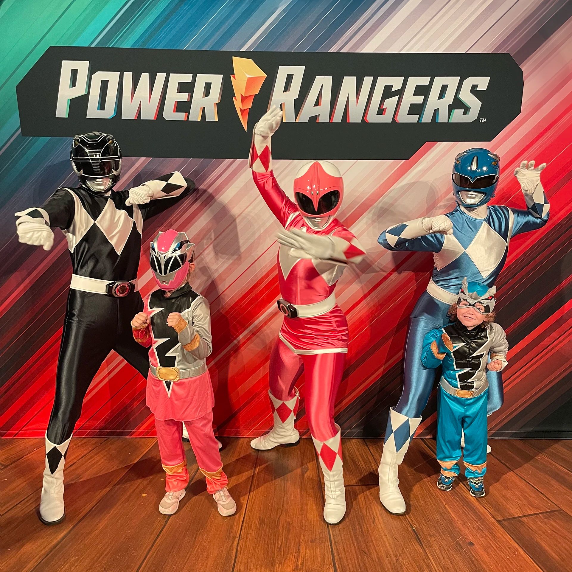 Black Ranger, Pink Ranger and Blue Ranger posing with 2 kids in Power Ranger costumes